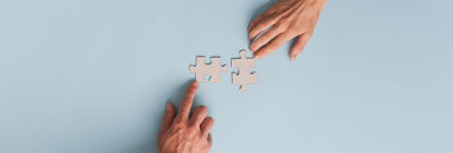 Two hands putting puzzle pieces togerther. 