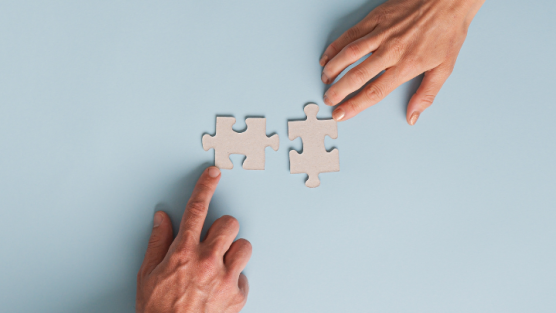 Two hands putting puzzle pieces togerther. 