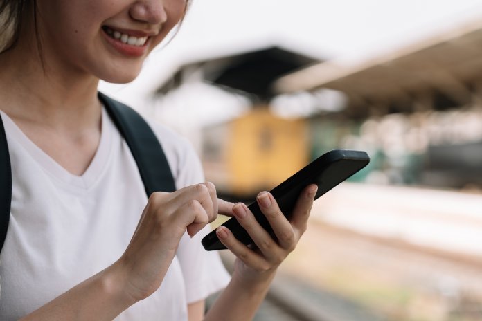 A smiling person reading a text message from a phone