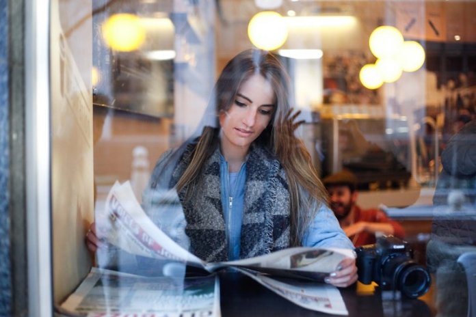 Woman reading newspaper in a restaurant