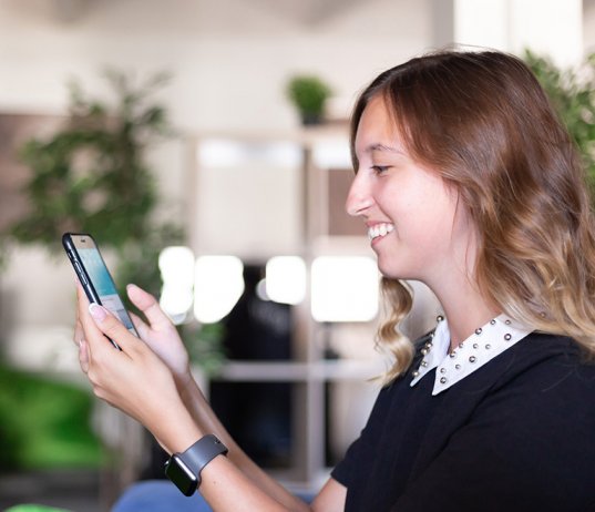 Why to use media analysis – a woman smiling and using her smart phone